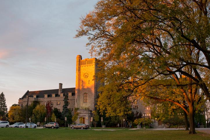 Johnston Building during sunset with a tree in the foreground and cars parked in front