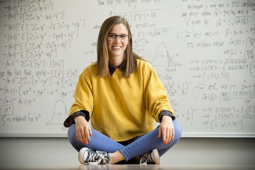 Image of student sitting on floor with legs crossed and math equations in background