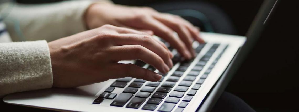 A close up of a persons hands typing on a keyboard