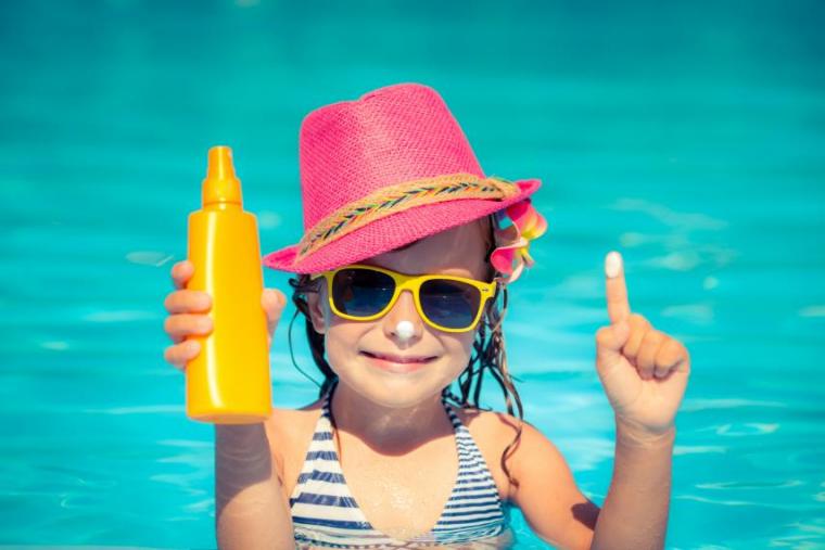 Child in a swimming pool holding sunscreen