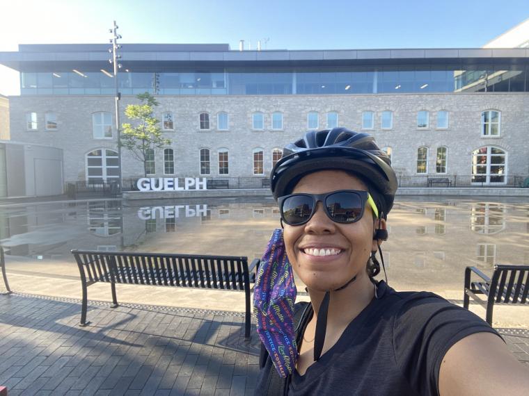 Dr. Elyse Hill biking in front of Guelph City Hall on a sunny day