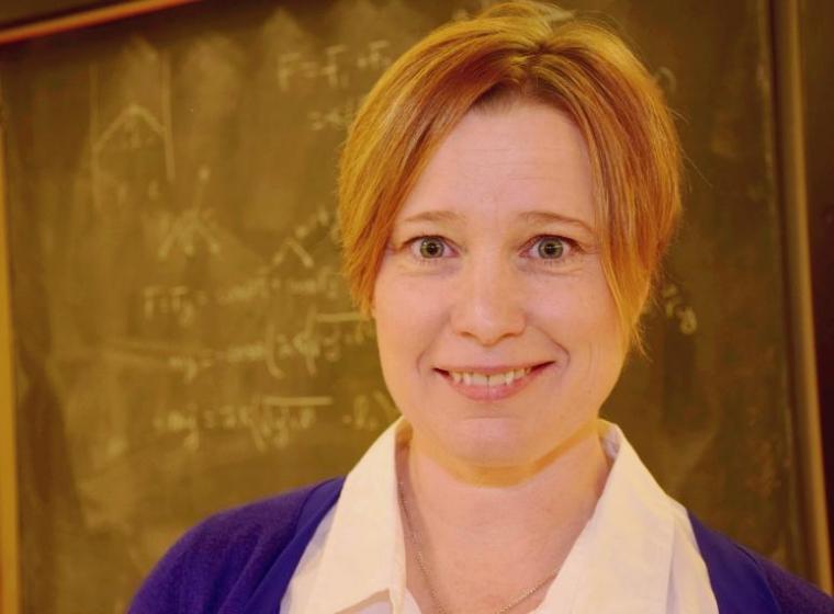 Physics professor Joanne O'Meara in front of a chalkboard.