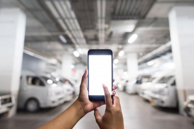 Photograph of an underground parking lot with a person's hands holding a smart phone