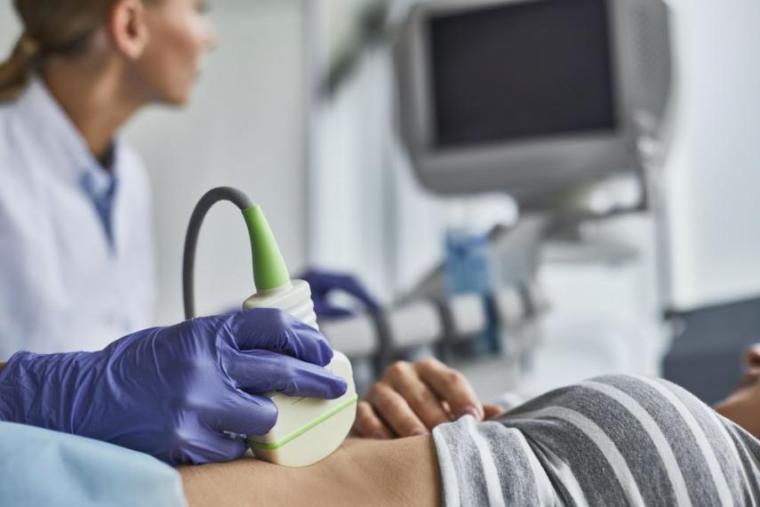 A patient receives an ultrasound examination from a woman.