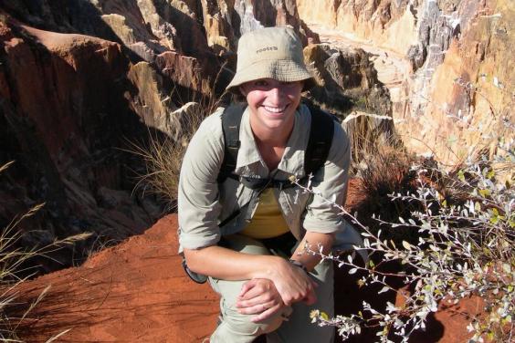 Image of Keriann crouching with rugged landscape in background