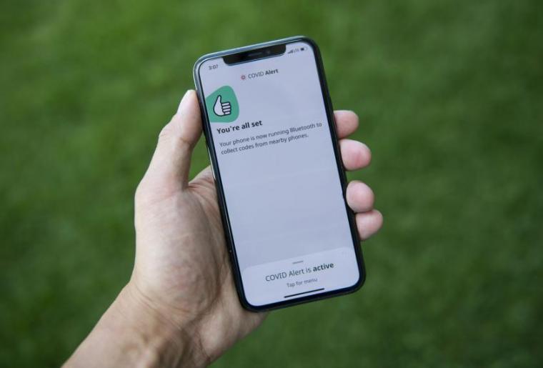 Image of person holding phone with provincial COVID-19 tracing app