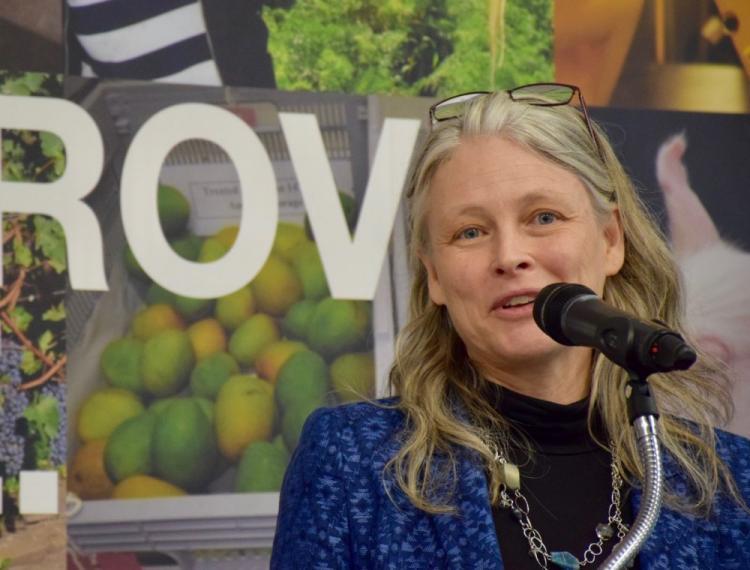 Image of Andrea Bradford talking into microphone in front of Improve Life banner