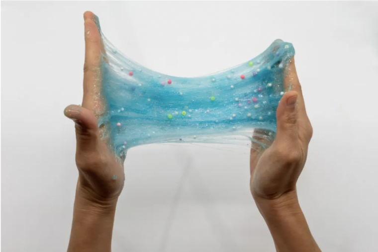 Two hands stretching blue slime.
