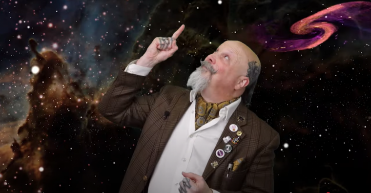 Orbax looking and pointing up in front of galaxy background.