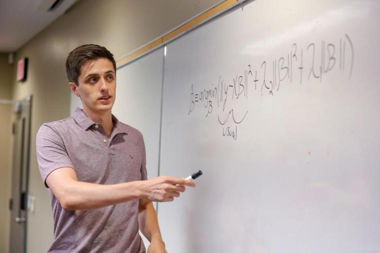 Dr. Justin Slater pointing to a white board.