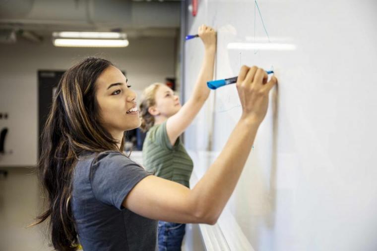 Female student writing on a whiteboard.
