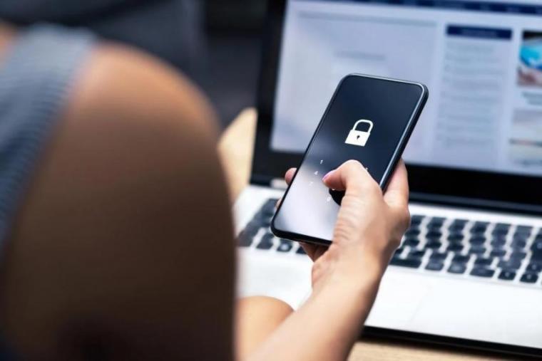 Person holding phone in front of a laptop.