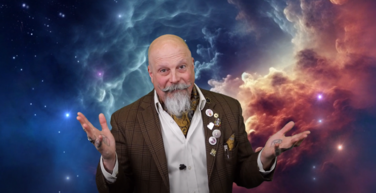 Orbax standing in front of a blue and pink sky backdrop.