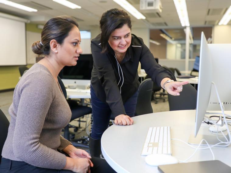Dr. Rozita Dara points at a computer while a staffer looks at the screen