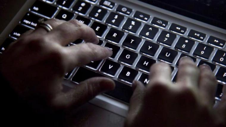 Two hands typing on a laptop keyboard.