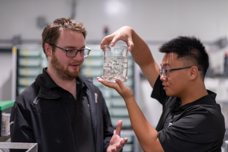 Two researchers looking at a bottle. 