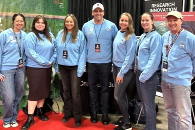 Seven producers wearing blue sweatshirts and smiling at the camera.