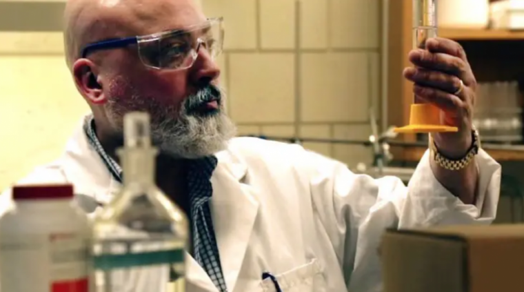 Image of scientist looking at a beaker in his hand