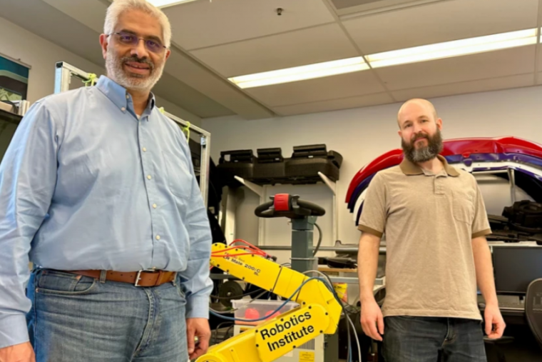 Dr. Medhat Moussa and another U of G researcher pose in lab with yellow robotic arm.