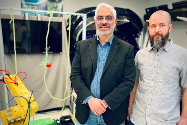 Two researchers posing with their yellow robot. 