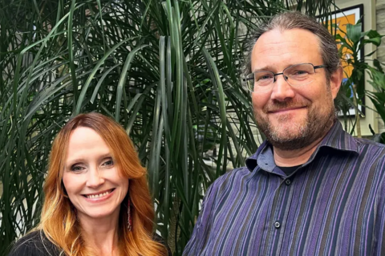 Two people posing infront of large plant.