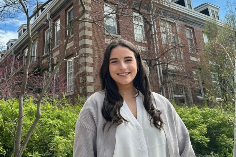 Madison Hughes in front of university building during the spring, smiling at the camera.