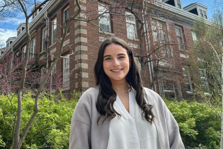 Madison Hughes in front of university building during the spring, smiling at the camera. 