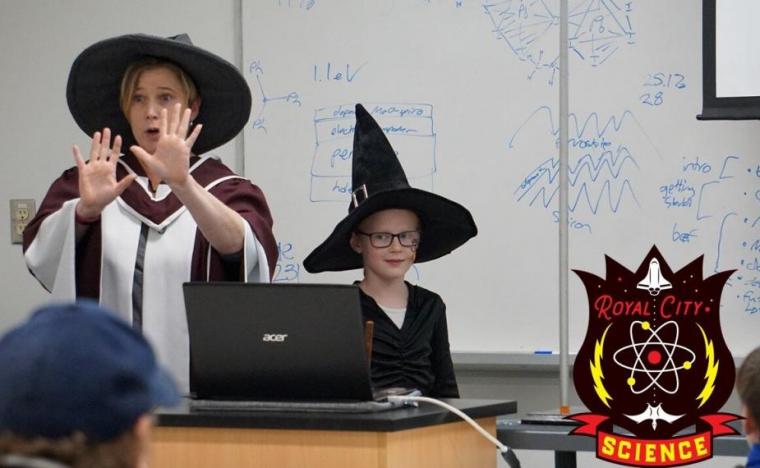 Image of Dr. Joanne O’Meara and a child at the front of a classroom in witch hats 