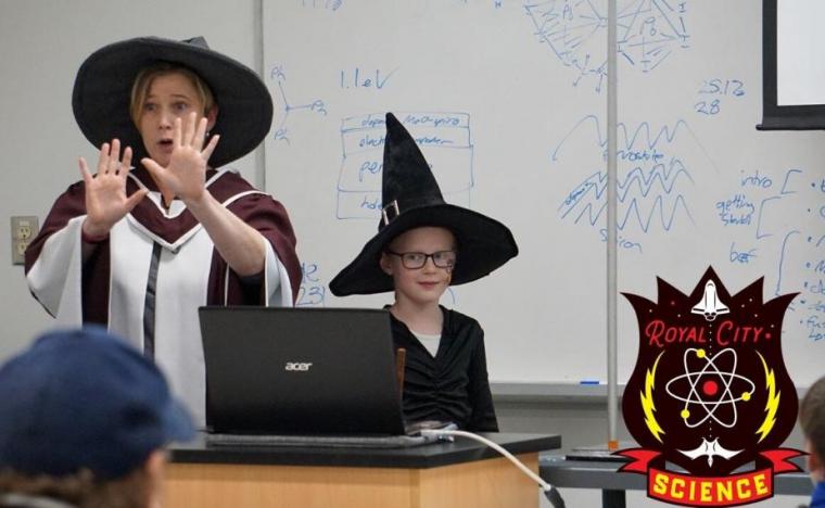 Image of Dr. Joanne O’Meara and a child at the front of a classroom in witch hats