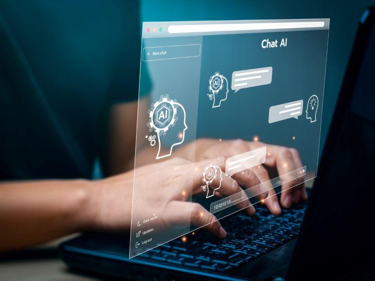 A laptop has a digital hologram above it displaying chat AI and and various cyber logos, while a man sits at the laptop typing on it