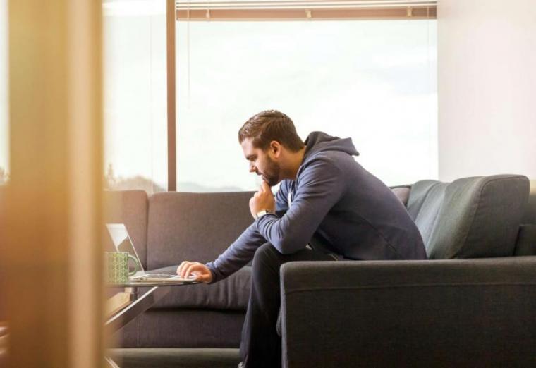 Image of person sitting on couch looking at laptop screen