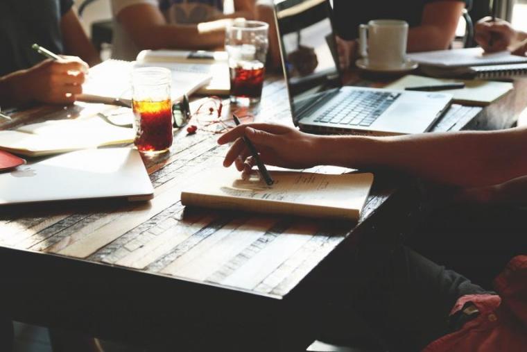 Image of people collaborating with papers across table