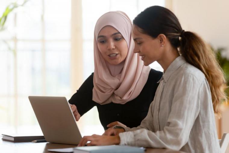 Stock image of two women working together while looking at a computer