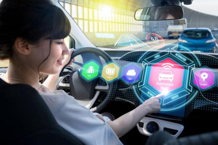Woman sitting in self-driving car with colourful, stylized screens in front of her.