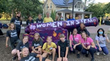 Several creative encounters summer campers pose in front of the U of G cannon, freshly painted purple with #WomenInSTEM