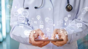 Composite image of person holding iPad in doctor's uniform with data emitting from screen