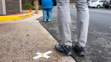 Image of person standing next to "X" on pavement with another person far ahead of them