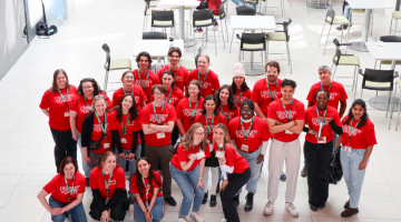 Group of volunteers posing in red shirts in Engineering Atrium.