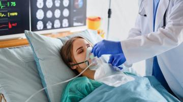 Person lying in hospital bed with oxygen mask