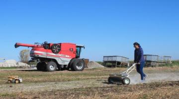 A person operates farming machinery on a farm