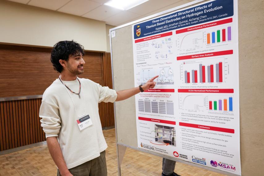 Hussain Jafri points to a diagram on his poster presentation.