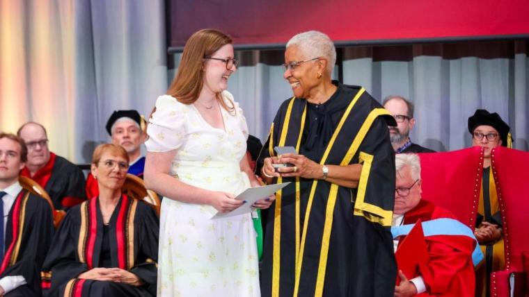 Megan Black accepts the Walter Vaughan Medal from Dr. Mary Anne Chambers infront of the platform party at convocation.
