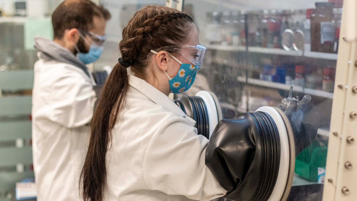 Two students working in a glove box in the Preuss Lab.