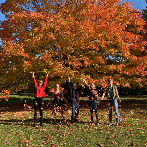No Exchange Agreement - 4 students throwing leaves in the air in fall