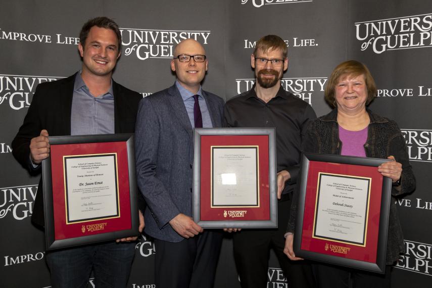 Honorees from left to right: Dr. Jason Ernst, Devin Gauthier, Mark George, and Dr. Deb Stacey [each holding a framed UofG award]