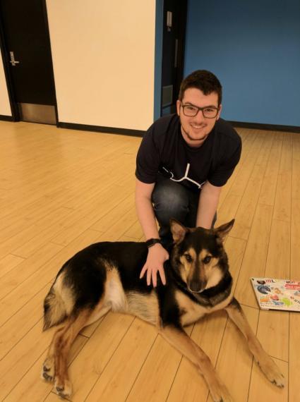 Marshall Asch crouching with a dogat the Left offices in Maple Ridge, British Columbia