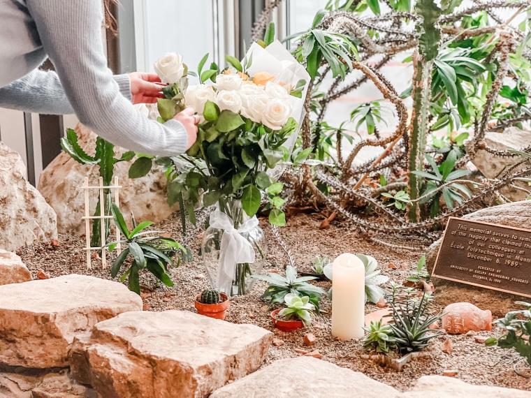 person adding a white rose to the memorial garden in Thornbrough Building.