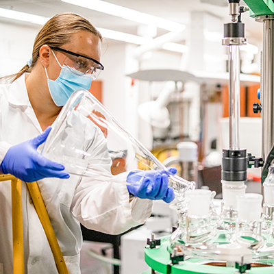 female student pouring liquid out of a beaker