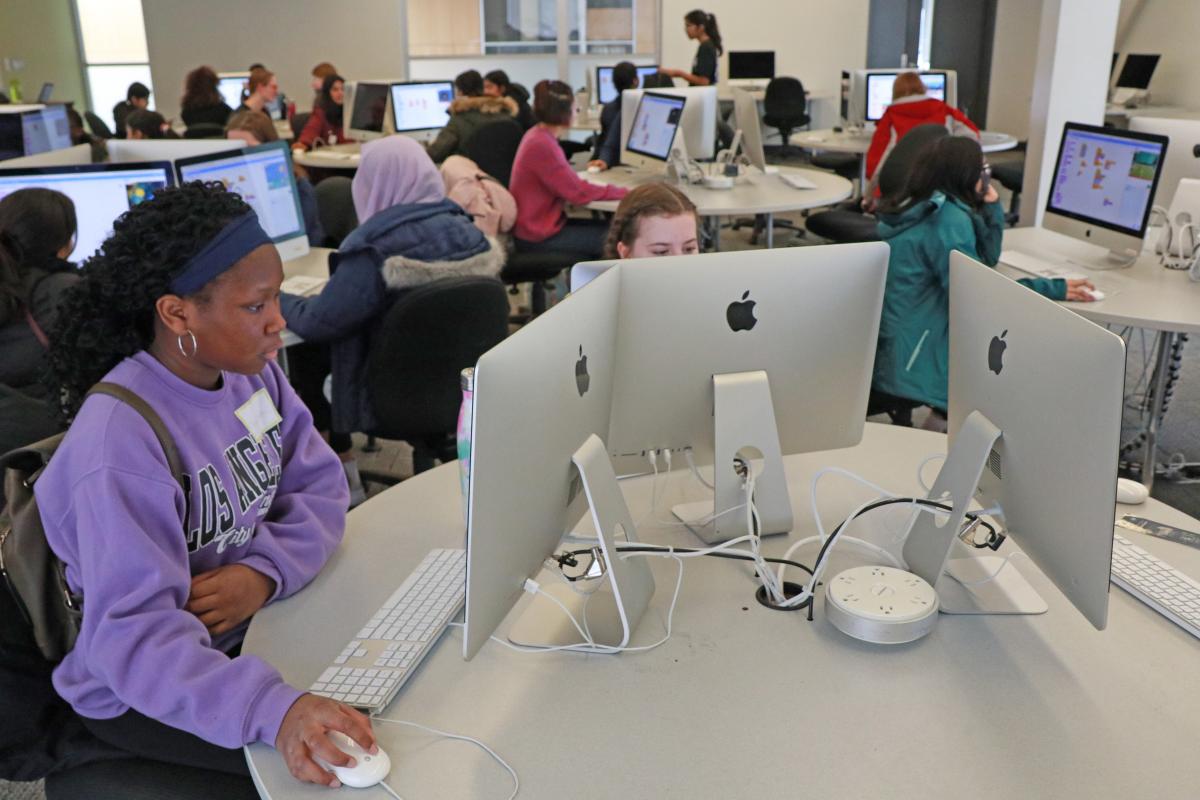 Young girls completing coding activities in a computer lab.