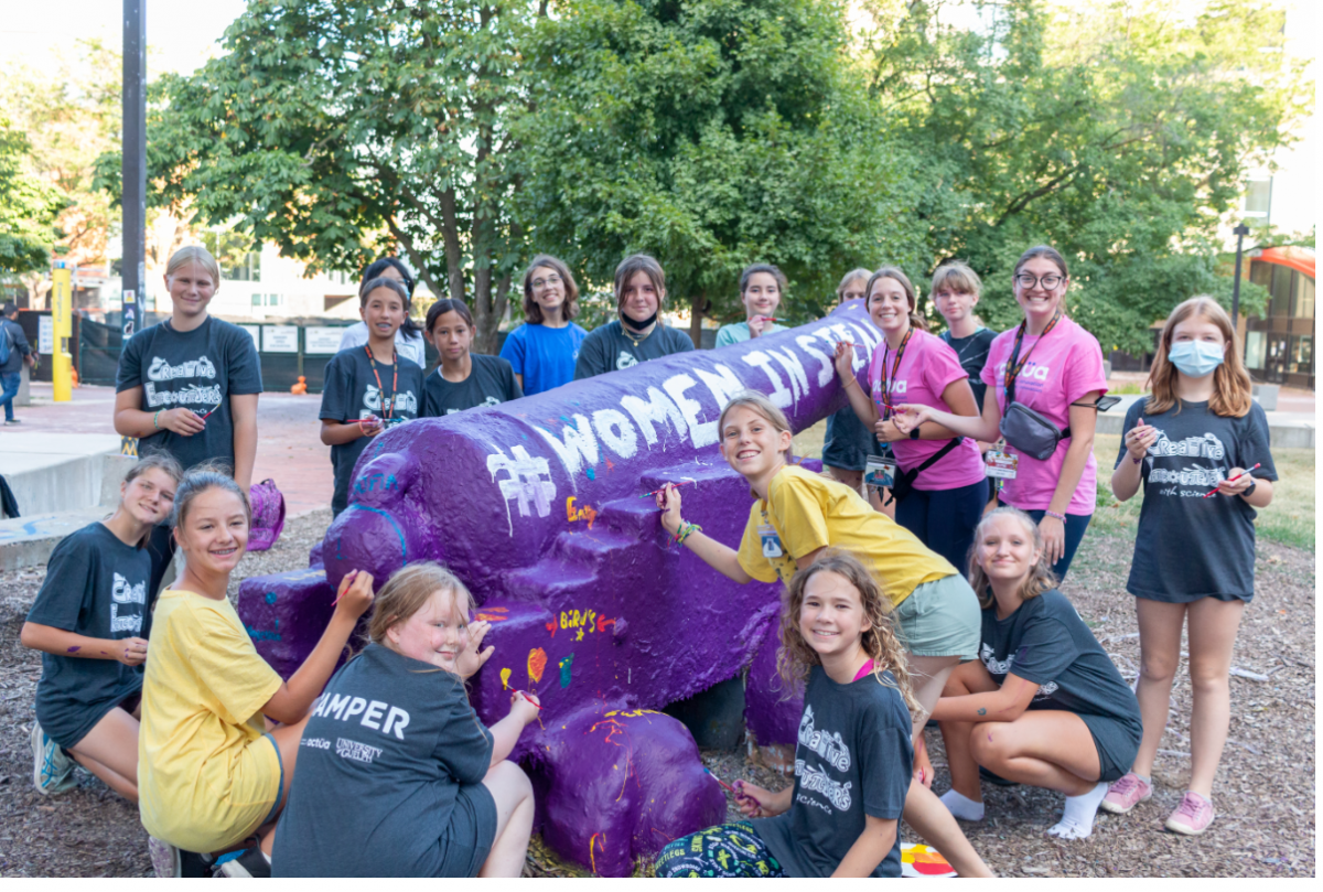 Young girls posing around the University of Guelph cannon. The cannon has been painted, reading "#WOMEN IN STEM".